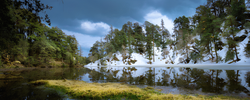 Frozen Brahmatal lake surrounded by snow-covered mountains with trekkers walking along the winter trail